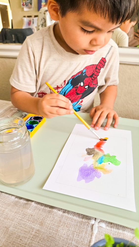 A child painting with watercolors at the homeschool table